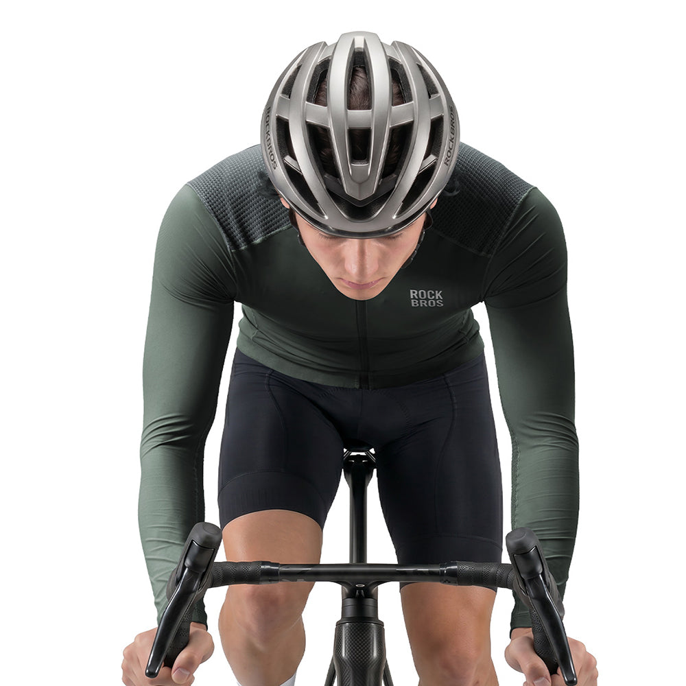 A cyclist in a dark green and black long-sleeve cycling jersey with black shorts, wearing a silver helmet, captured from a high-angle front view on a white background. The jersey features the brand name 'ROCK BROS' on the chest. #Color_Gray