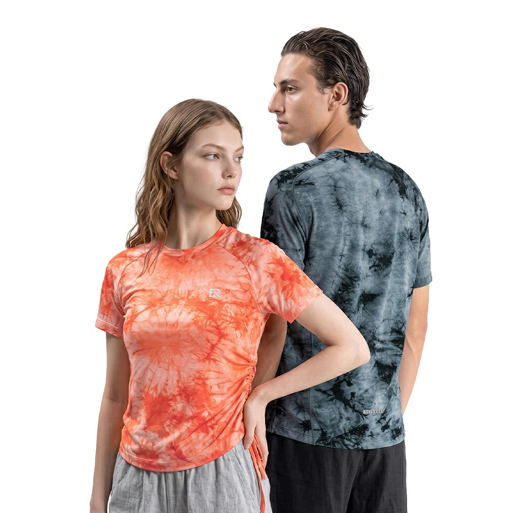 Two models wearing athletic t-shirts with tie-dye patterns, one in orange and the other in a blue-gray marbled pattern, against a solid white background.