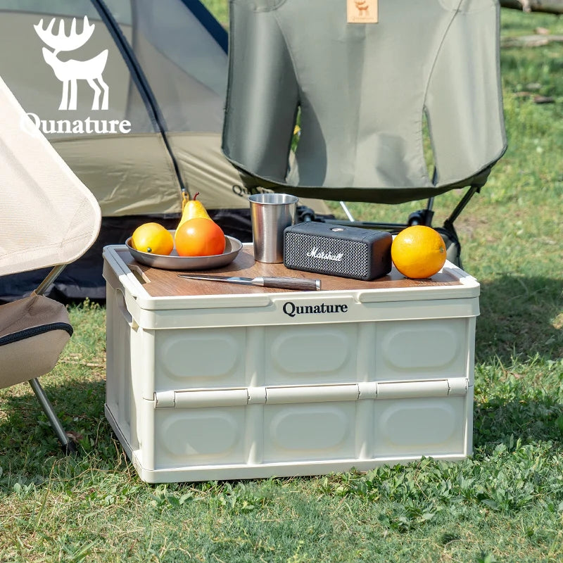 Camping scene with a Qunature cooler box, fruit, and a Marshall speaker in front of a tent.