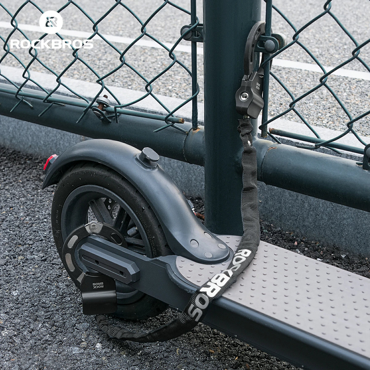 Black scooter with visible branding against a chain-link fence background