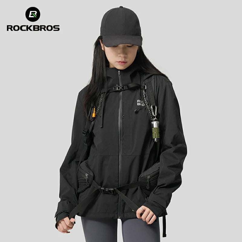 Person wearing a black jacket and cap with a backpack, standing against a gray background, featuring the RockBros brand. #Color_black