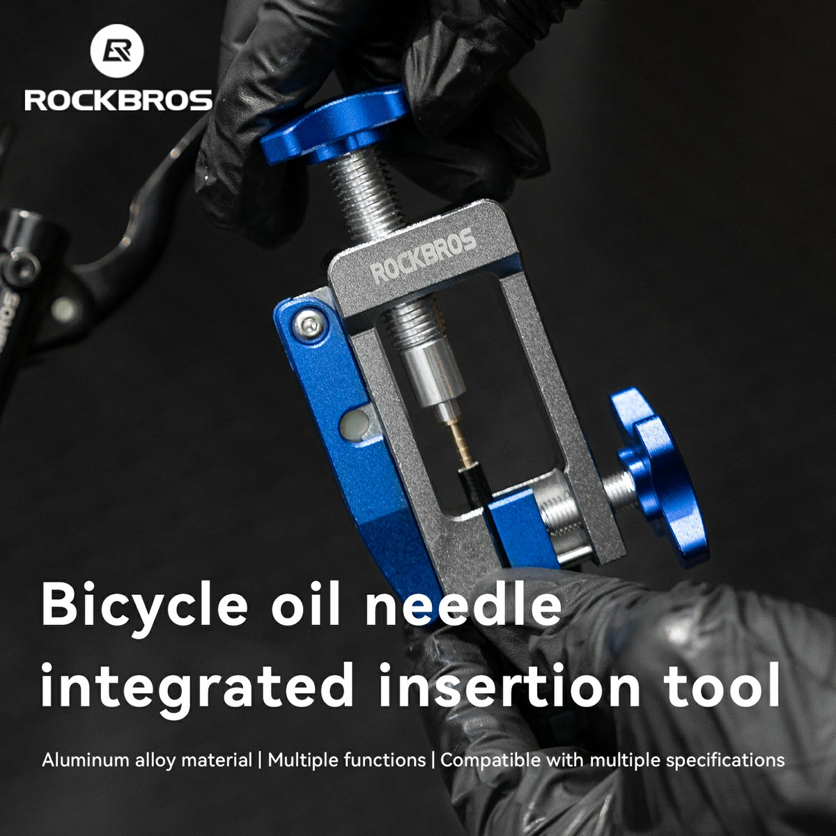 A close-up of a Rockbros bicycle oil needle integrated insertion tool being held by gloved hands against a dark background, with the Rockbros logo and product text overlaid on the image.