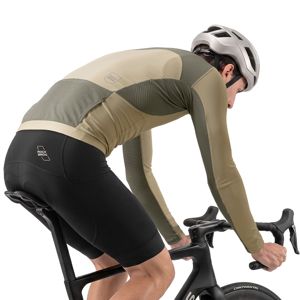 A cyclist in a beige and olive green long-sleeve jersey and black shorts, leaning forward on a road bike against a white background. #Color_khaki
