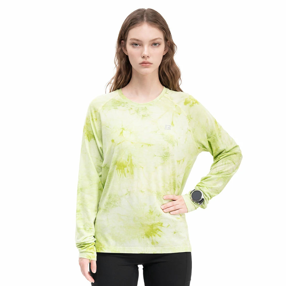 A woman modeling a light lime green long-sleeve athletic shirt with a yellow-green tie-dye pattern, paired with black leggings, against a solid white background. 