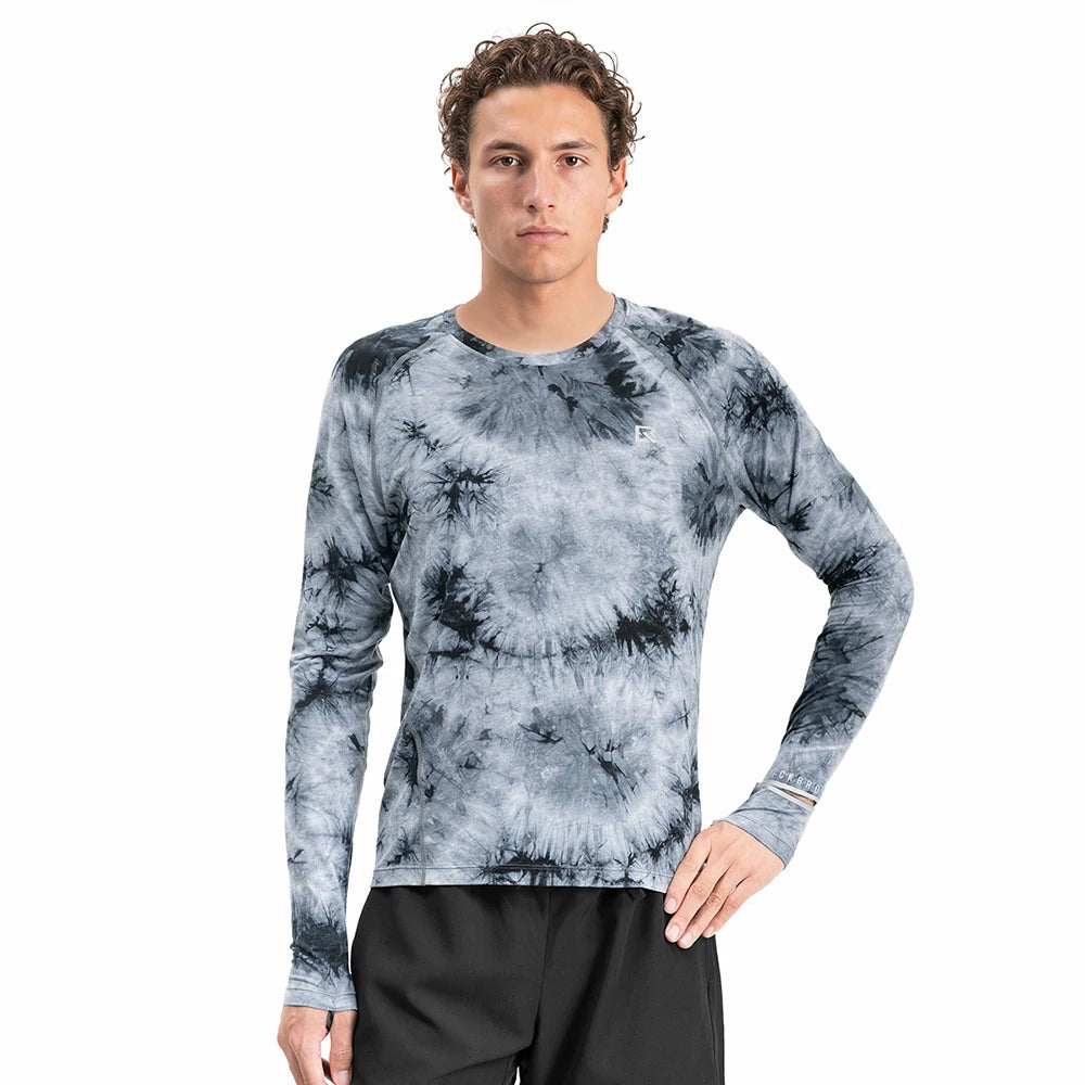 A man modeling a long-sleeve crewneck shirt with a blue and gray tie-dye pattern, paired with black athletic shorts, against a solid white background.