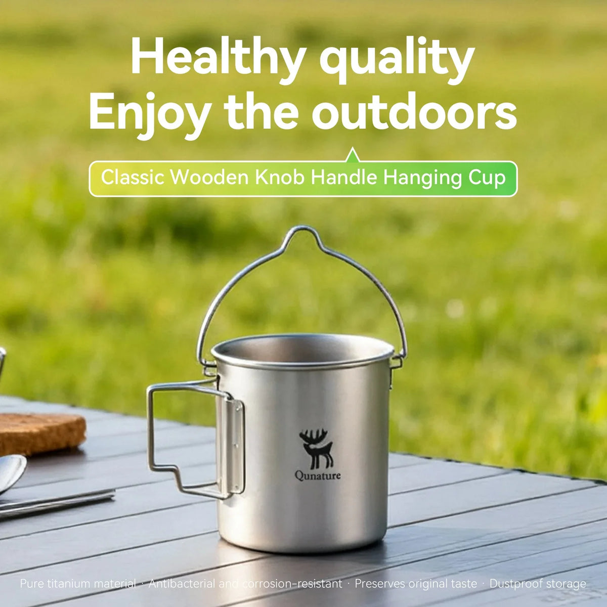 Stainless steel hanging cup with wooden knob handle on a wooden table outdoors.