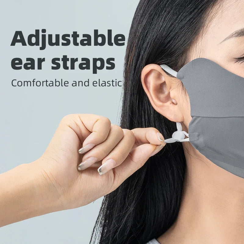 Person adjusting a gray face mask with adjustable ear straps on a light gray background